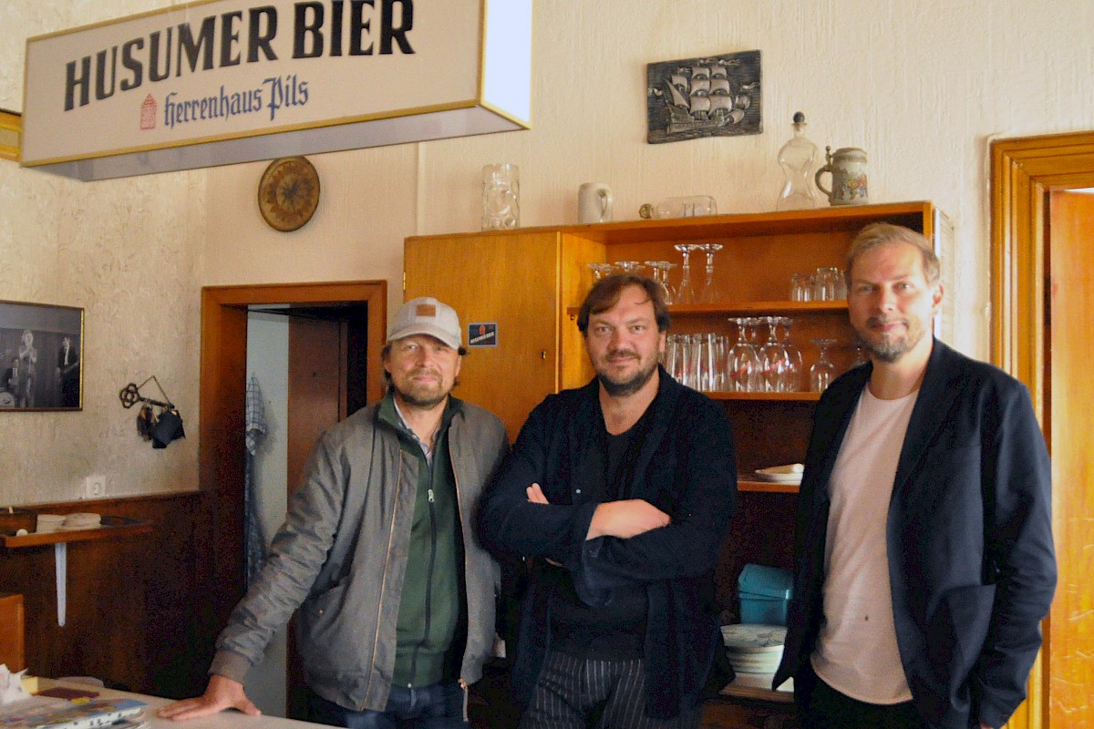Director Lars Jessen and lead actor Charly Hüber with MOIN CEO Helge Albers at the "Mittagsstunde" shoot. Copyright: Kai Labrenz | MOIN Filmförderung